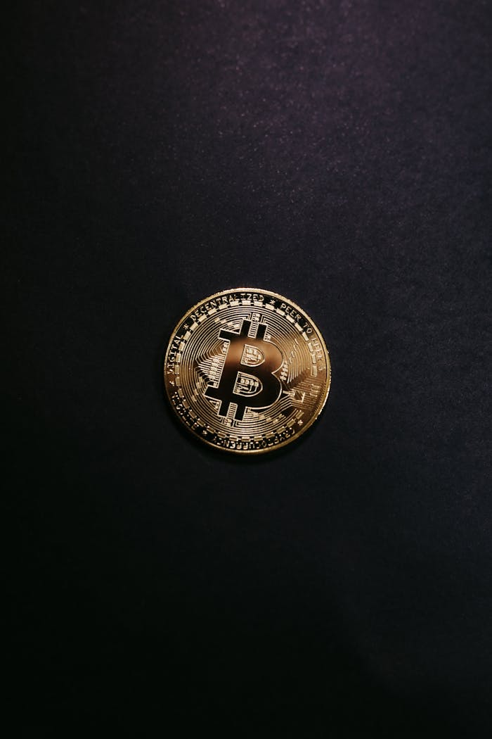 Close-up of a shiny gold bitcoin on a black background, symbolizing cryptocurrency.