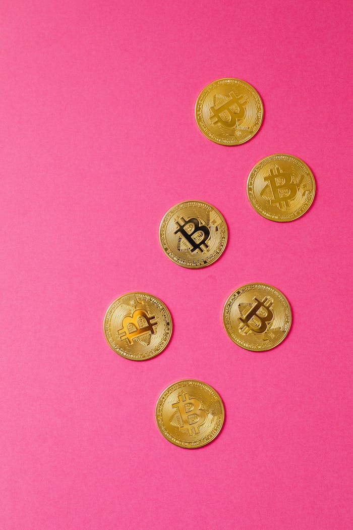 Gold Bitcoin coins arranged on a striking pink background, showcasing cryptocurrency appeal.